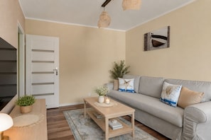 Una sala de estar con un sofá, una mesa de centro, una lámpara y una puerta.
