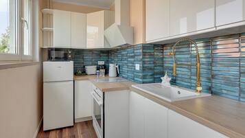 Une cuisine moderne avec des meubles blancs, une cuisinière encastrée et un dosseret de carrelage bleu.