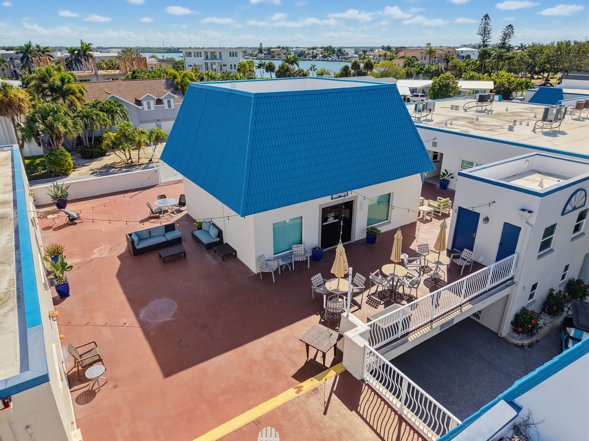 A hotel with a blue-roofed building, outdoor seating, and a view of the surrounding area.