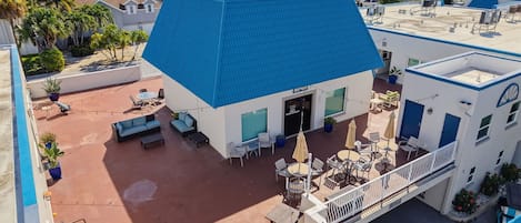 A hotel with a blue-roofed building, outdoor seating, and a view of the surrounding area.