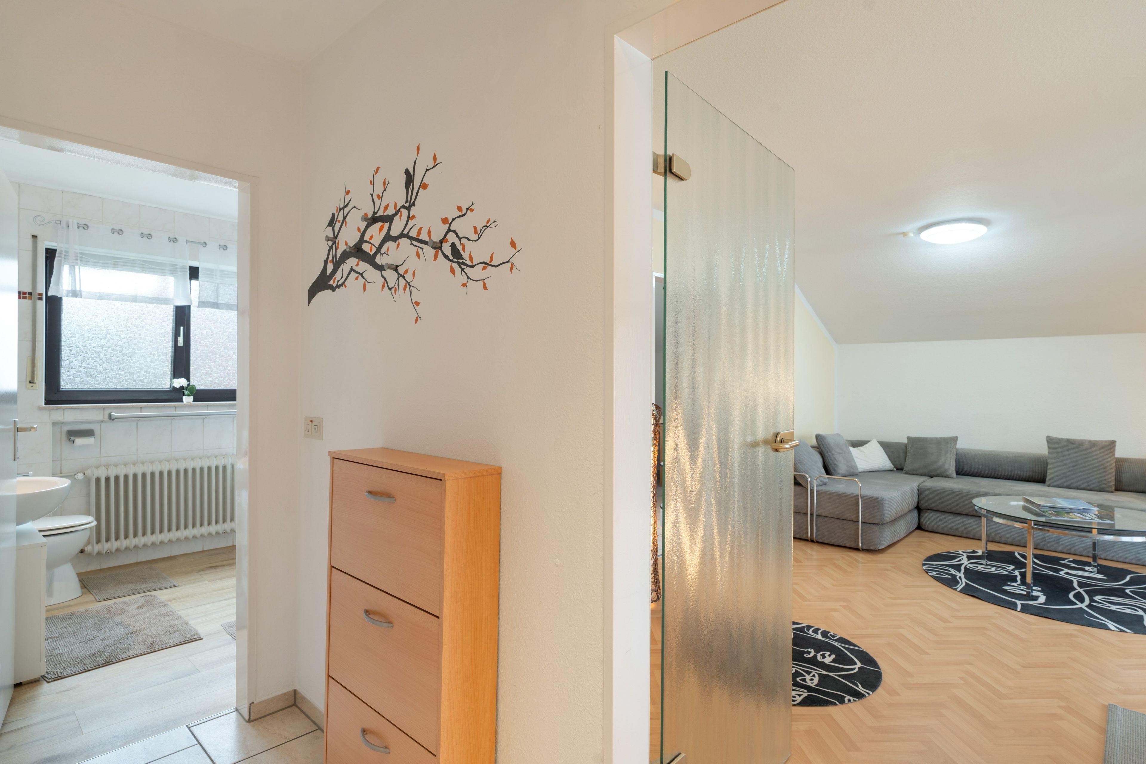 Eine moderne Wohnung mit Küche, einem Wohnbereich inklusive Sofa und Couchtisch sowie einem Holzschrank.