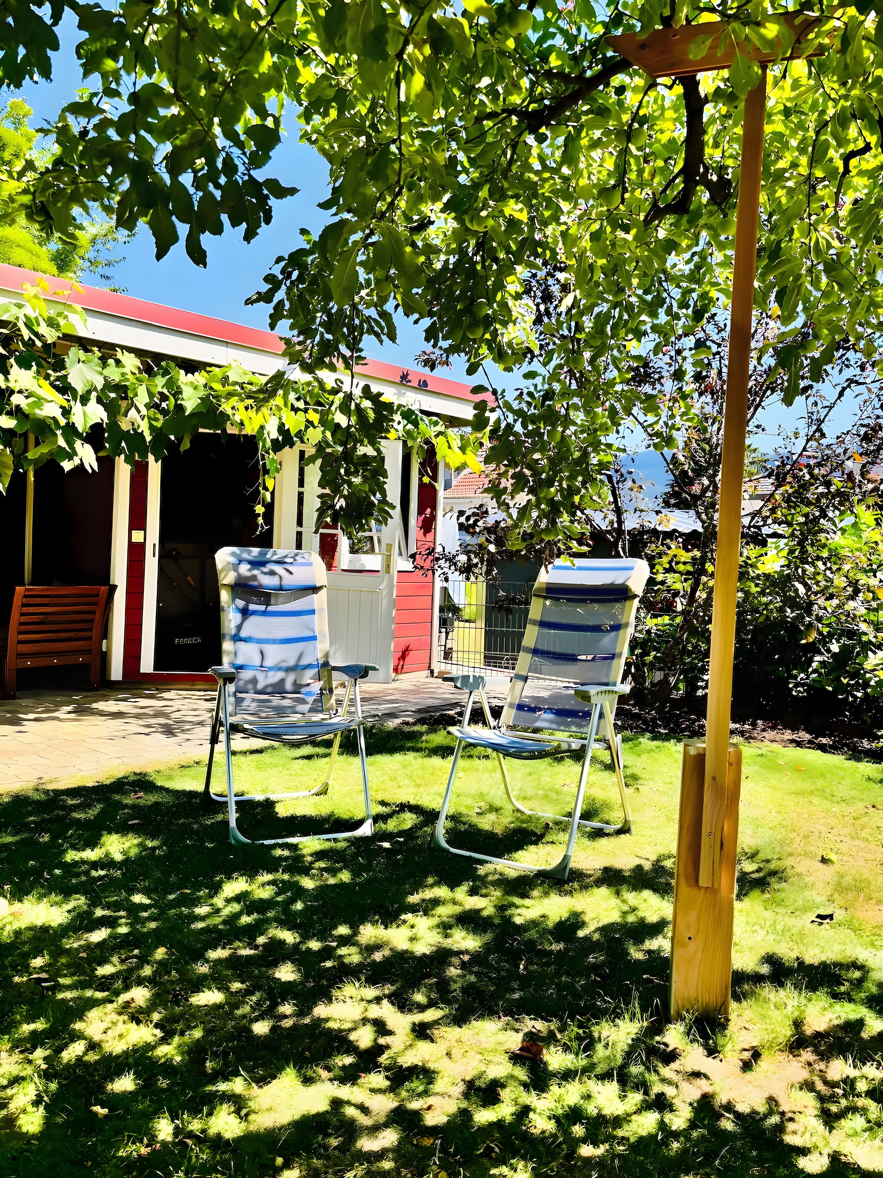 Eine Terrasse mit zwei Metallstühlen und einem Holzpfosten.