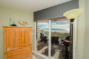 A room with a wooden cabinet, a sliding glass door leading to an outdoor seating area with a view of the beach. - Amic 42 2 Bedroom Condo (Bradenton Beach)