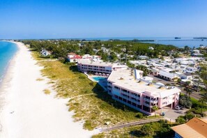 A beachfront hotel with multiple buildings, a swimming pool, and a pier in the background. - Amic 42 2 Bedroom Condo (Bradenton Beach)