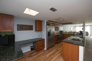 Une cuisine moderne avec des meubles en bois, un réfrigérateur en acier inoxydable et un plan de travail en granit noir.