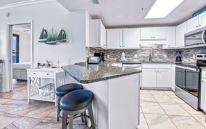 Una cocina moderna con gabinetes blancos, encimera de granito y horno empotrado.