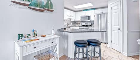 Una cocina moderna con una isla central, taburetes de bar y elementos decorativos.