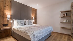 A modern bedroom with a large bed, wooden paneling, and built-in lighting. - Premium Apartment in the City Center (Kirchberg in Tirol)