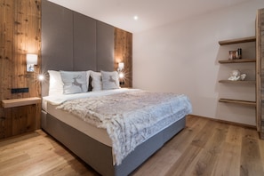 Ein modernes Schlafzimmer mit einem großen Bett, Holzvertäfelung und eingebauter Beleuchtung.