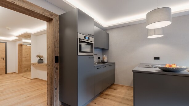 A modern kitchen with a built-in oven, a grey countertop, and a wooden floor. - Premium Apartment in the City Center (Kirchberg in Tirol)