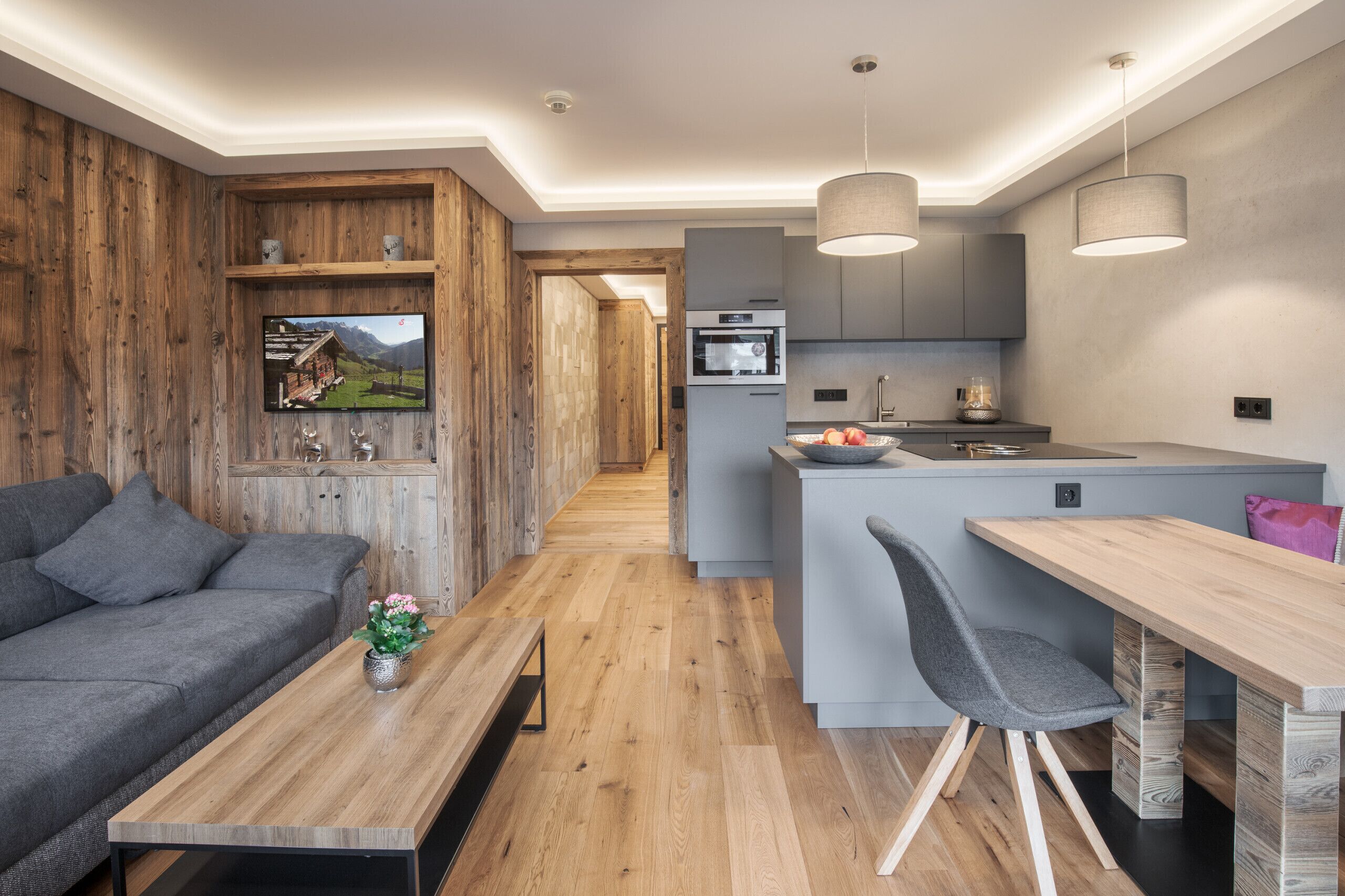 A modern kitchen with a central island, grey cabinetry, and a built-in oven.