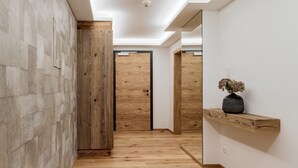 A hallway with wooden flooring, a wooden door, and a mirror on the wall. - Premium Apartment in the City Center (Kirchberg in Tirol)