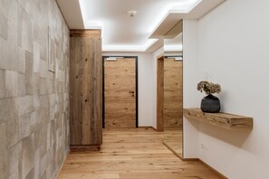 Ein Flur mit Holzboden, einer Holztür und einem Spiegel an der Wand.