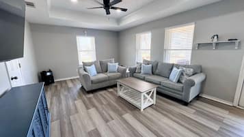 Ein Wohnzimmer mit zwei grauen Sofas, einem Couchtisch und einem Deckenventilator.