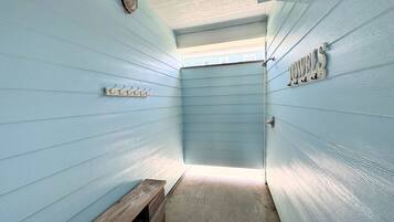 A narrow hallway with a bench, a towel rack, and a door at the end.