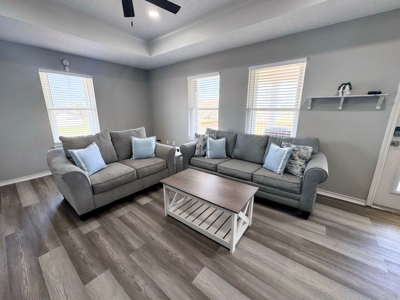 A living room with two grey sofas, a coffee table, and a ceiling fan.