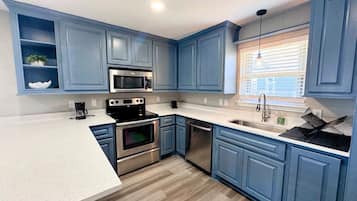 A kitchen with blue cabinets, stainless steel appliances, and a white countertop.