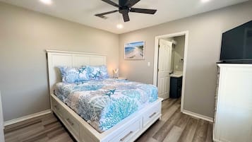 A bedroom with a bed, a ceiling fan, a nightstand, a door, and a cabinet.