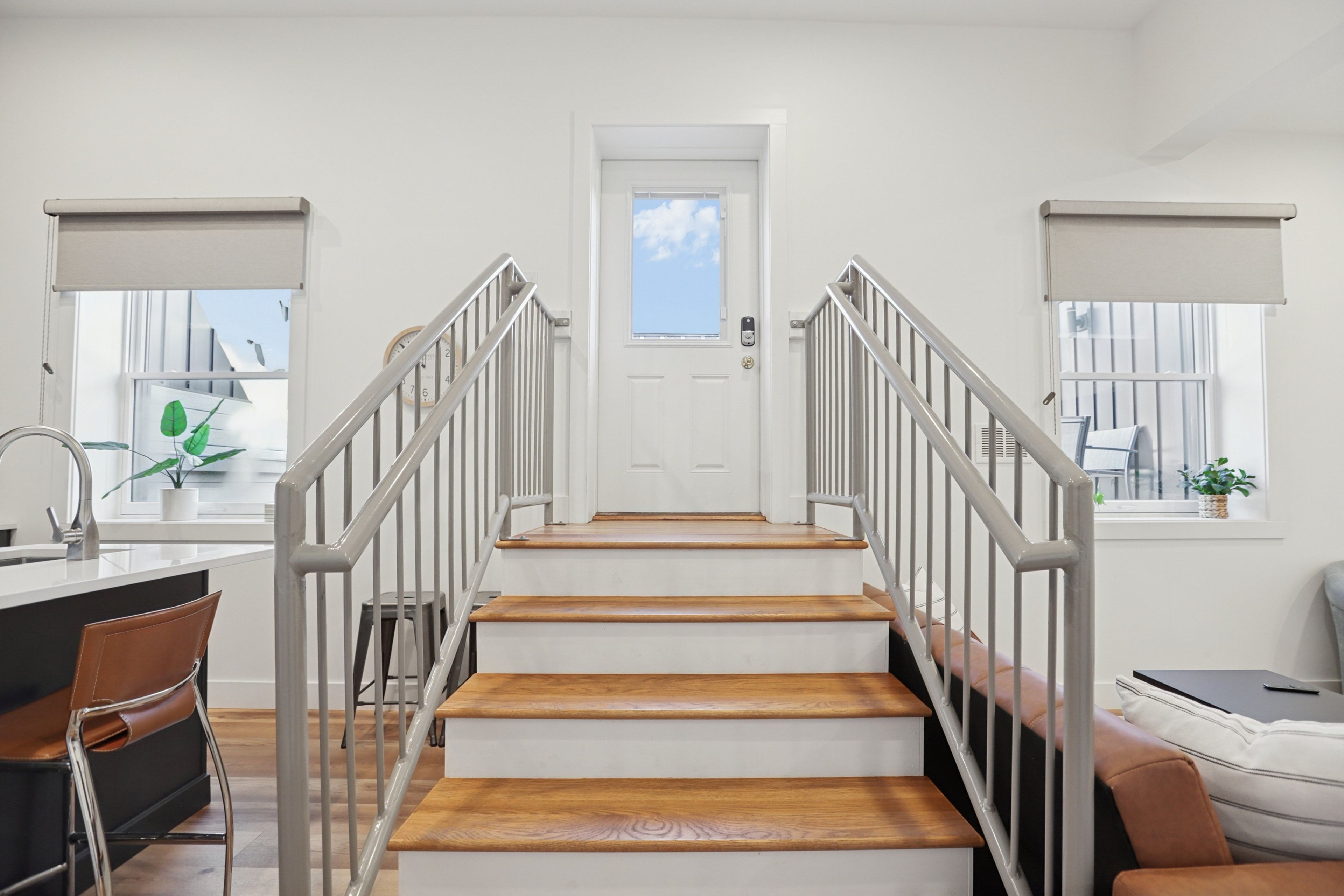 A staircase with a white door at the top, leading to a room with a window and a plant.