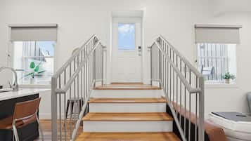 A staircase with a white door at the top, leading to a room with a window and a plant.