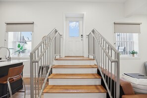 A staircase with a white door at the top, leading to a room with a window and a plant. - Stylish Downtown Unit With Historic Charm 3 Bedroom Apts (Bloomington)