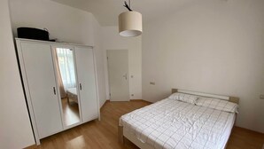 A bedroom with a bed, wardrobe, and a hanging light fixture. - Copy of To complete (Görlitz)