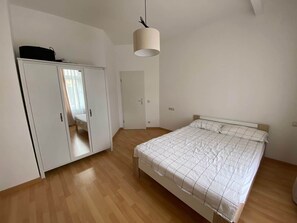 A bedroom with a bed, wardrobe, and a hanging light fixture. - Copy of To complete (Görlitz)