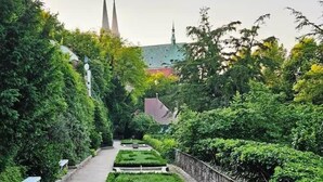 A garden pathway with a water feature, benches, and a distant church spire. - Copy of To complete (Görlitz)