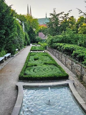 A garden pathway with a water feature, benches, and a distant church spire. - Copy of To complete (Görlitz)