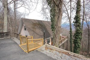 Une cabane dotée d’une terrasse en bois et d’un escalier menant à un porche.