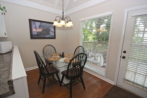 A dining area with a glass table, four chairs, a pendant light, a framed picture on the wall, and a door with a window. - Viewcatcher 2 Bedroom Cabin (Gatlinburg)