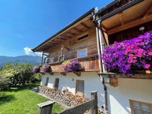 A wooden chalet with flower boxes on the balcony, a wooden fence, and a mountain in the background. - Seebichlhof 2 - Lebenberg (Kitzbühel)