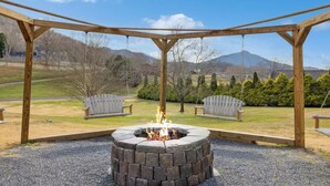 A wooden swing set with a fire pit in the center, surrounded by a gravel area with two Adirondack chairs. - Majestic Valley View 3 Bedroom Cabin (Sevierville)