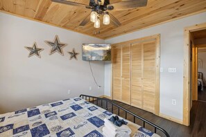 A bedroom with a bed, wooden wardrobe, ceiling fan, and wall-mounted TV. - Majestic Valley View 3 Bedroom Cabin (Sevierville)