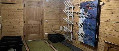 Een kamer met een houten deur, een wandrek met haken en een zwarte opbergbox.