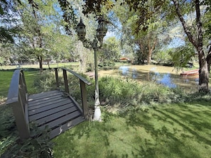 A wooden bench with a metal railing, a lamp post, and a pond with a red boat.