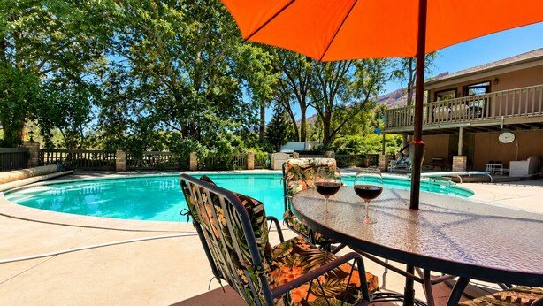 A poolside area with a table, chairs, and an umbrella.
