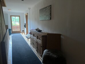 Ein Flur mit einer Holzbank, einem Korbstuhl und einem Schrank mit einer Schale darauf.