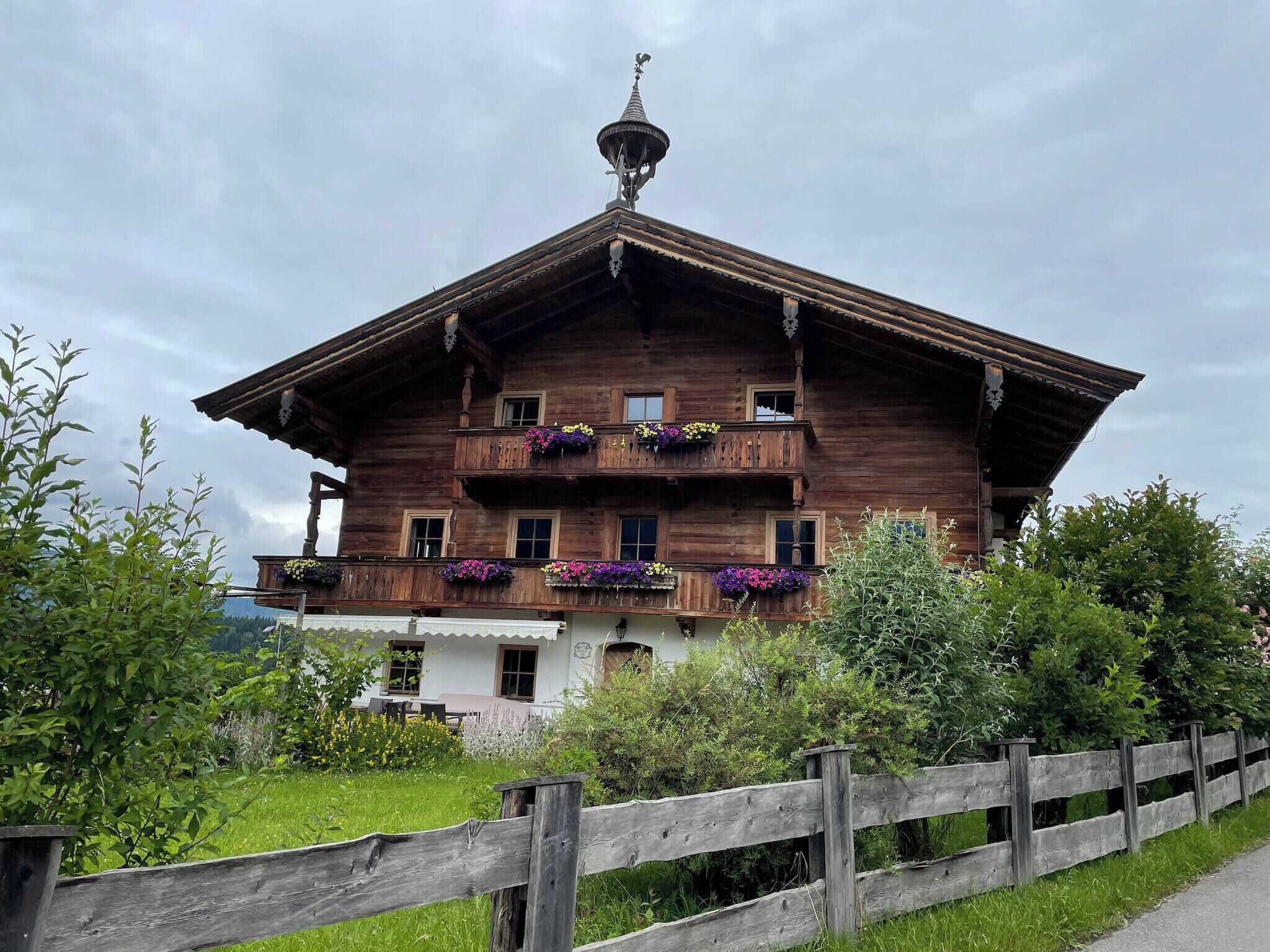 Ein traditionelles Holzhäuschen mit Balkon, umgeben von viel Grün.