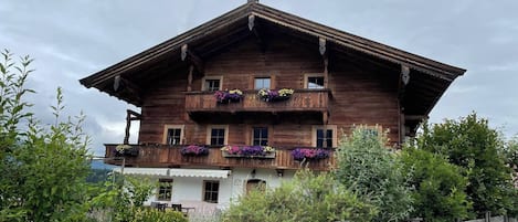 Un chalet de madera tradicional con balcón, rodeado de vegetación.