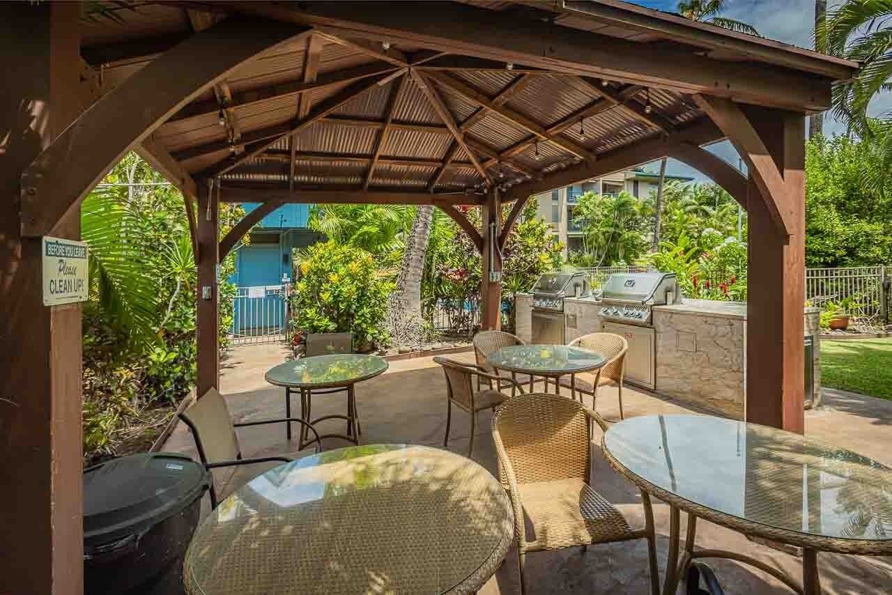Eine Terrasse im Freien mit überdachter Sitzgruppe, einem Grill und einem Schild mit der Aufforderung, vor der Abreise zu räumen.