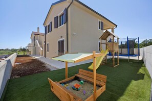 A residential property with a play area including a slide and climbing structure, a wooden playhouse, and a sandbox. - Apartment 'More' with Sea View, Wi-Fi and Air Conditioning (Bužinija)
