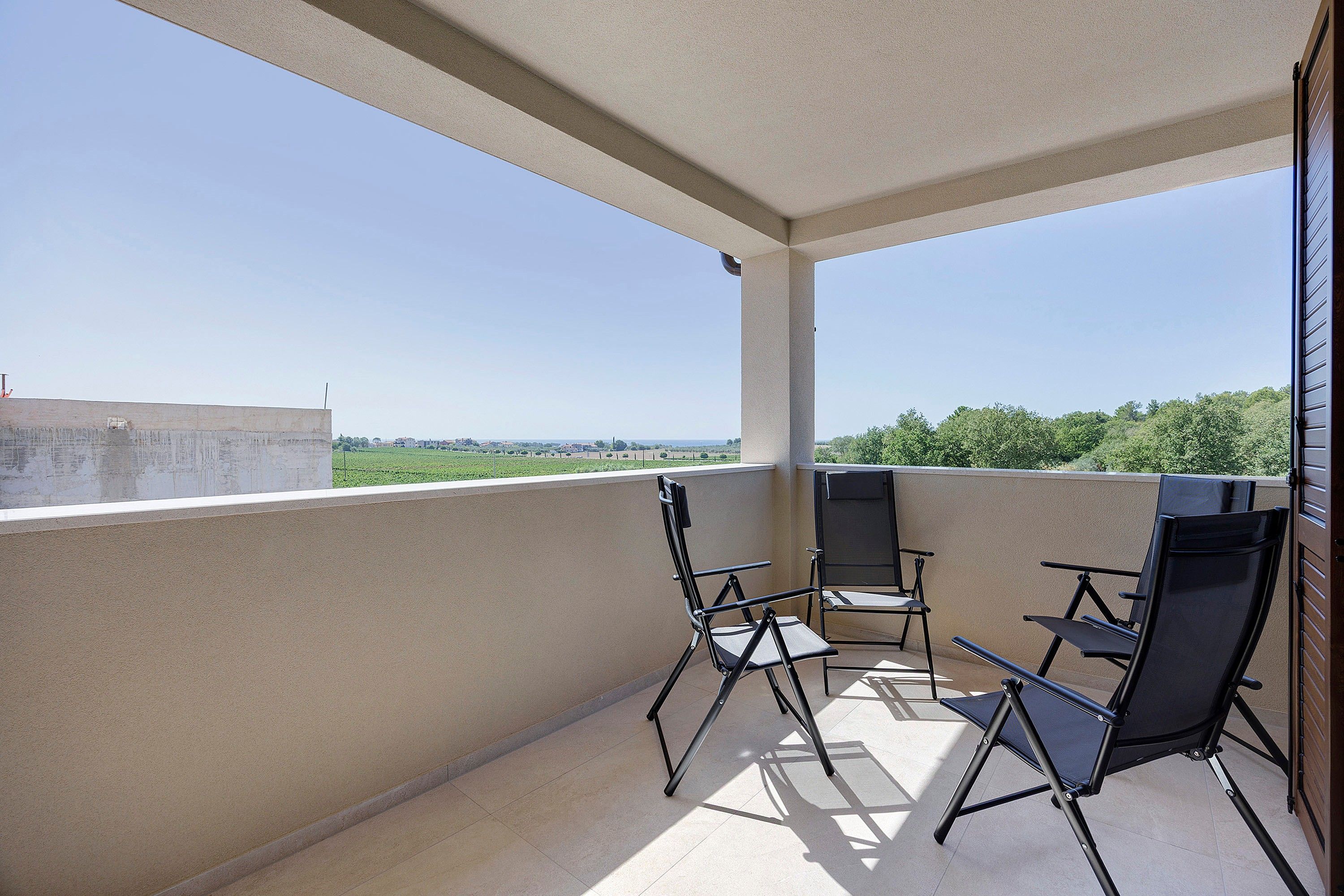A balcony with two chairs and a table, overlooking a green landscape.