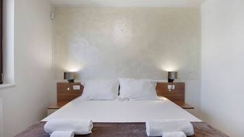 Une chambre d’hôtel avec un grand lit, deux lampes de chevet et deux serviettes enroulées posées sur le lit.