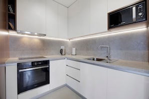 A modern kitchen with built-in appliances, a stainless steel sink, and a microwave.