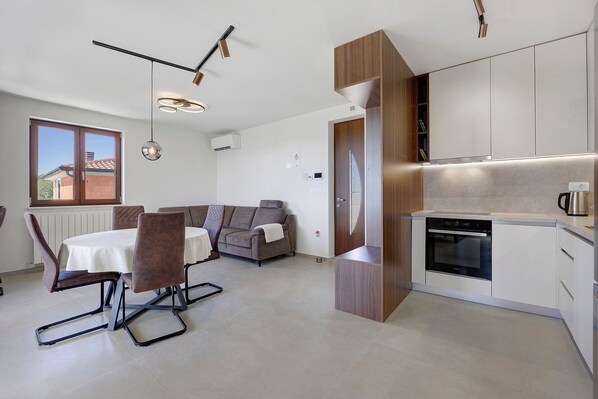 A modern kitchen with built-in appliances, a dining area with a table and chairs, and a living space with a sofa.