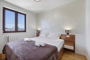 A bedroom with a bed, two bedside lamps, a window, and a radiator. - Apartment 'More' with Sea View, Wi-Fi and Air Conditioning (Bužinija)