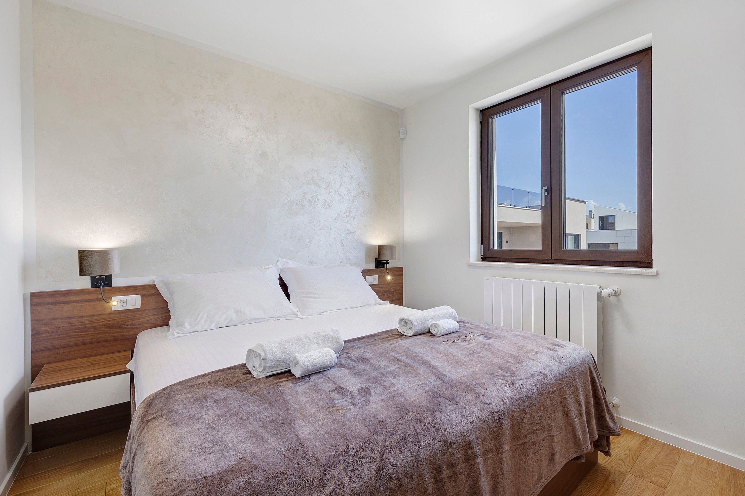 Una camera da letto con un letto, due comodini, una finestra e un termosifone.