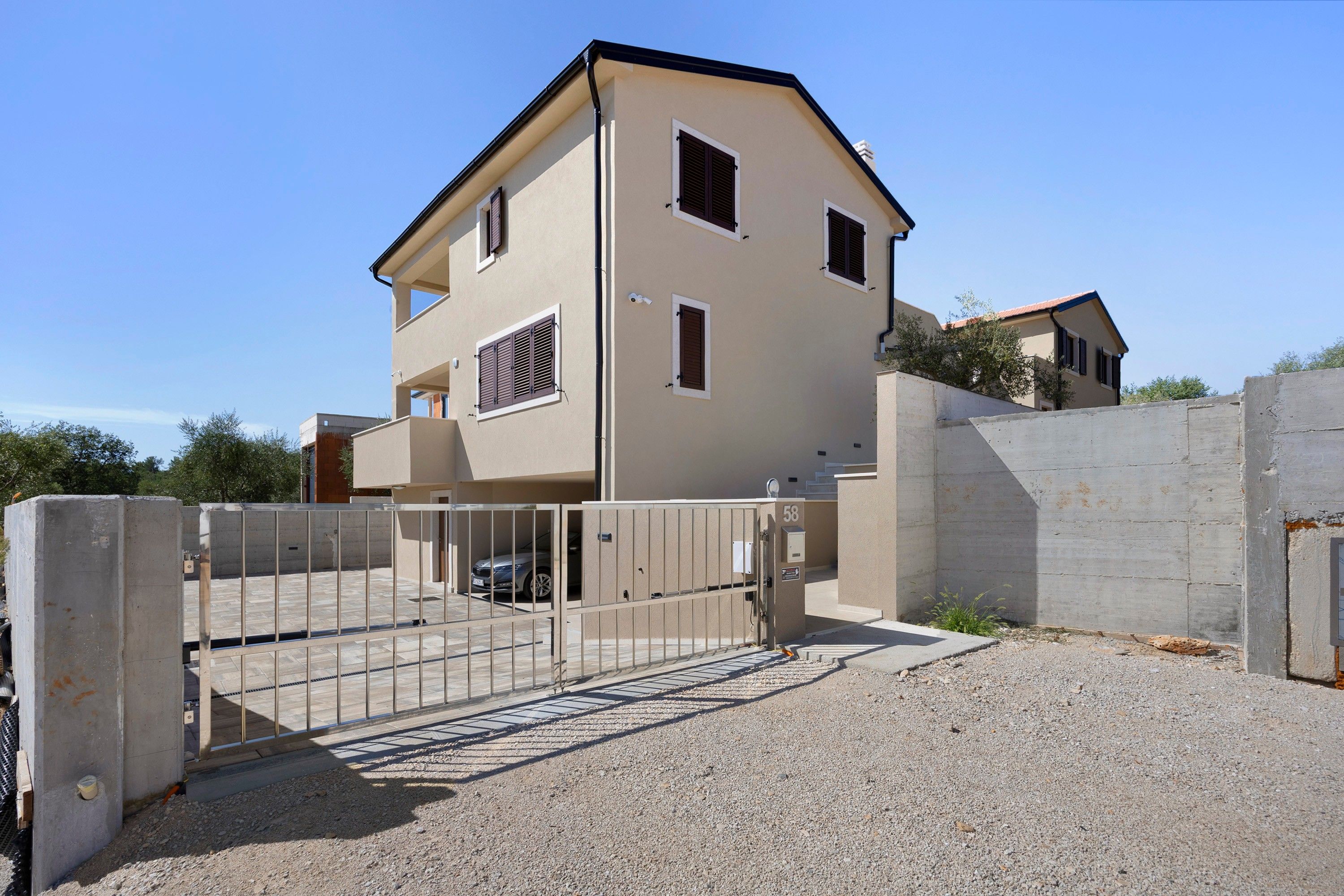 A two-story residential building with a gated entrance, a driveway, and a visible garage.