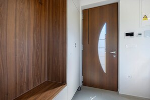 A hallway with a wooden wardrobe, a door with a reflective surface, and a wall with a thermostat and a power outlet. - Apartment 'Maslina' with Sea View, Wi-Fi and Air Conditioning (Bužinija)